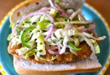 A Vegan Fried Chicken Sandwich featured on Namely Marly and topped with a savory slaw of of sliced jalapenos, pickled red onions, and high-quality olive oil.